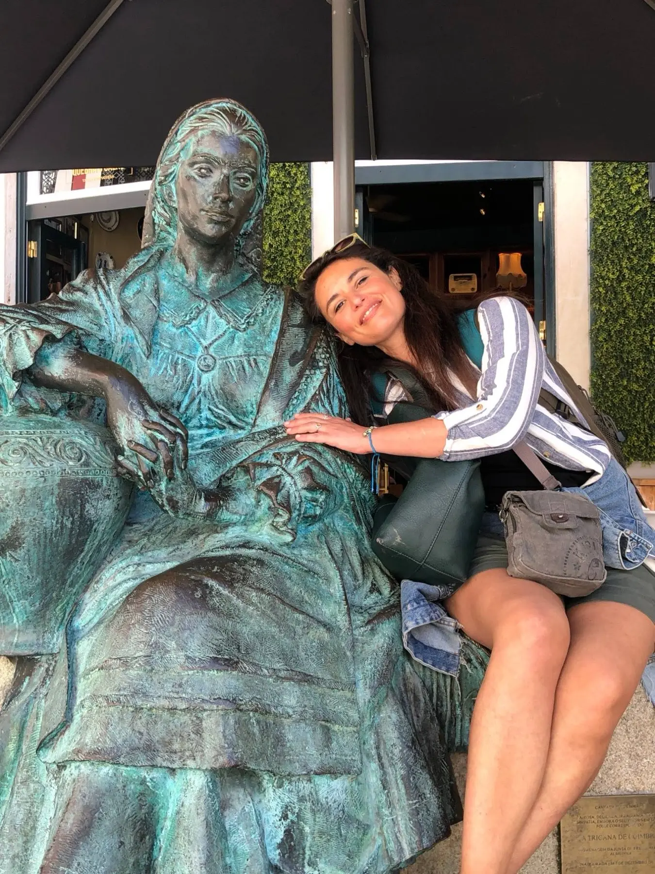 Ines leaning fondly on the shoulder of a bronze statue of a seated woman