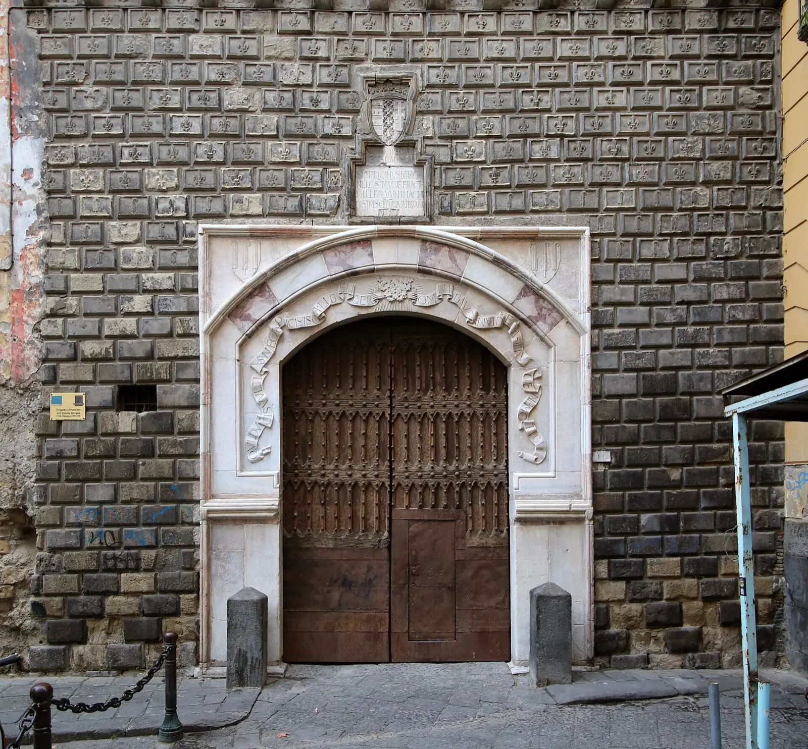 The pale stone arched doorway of Palazzo Penne set in a dark brick facade