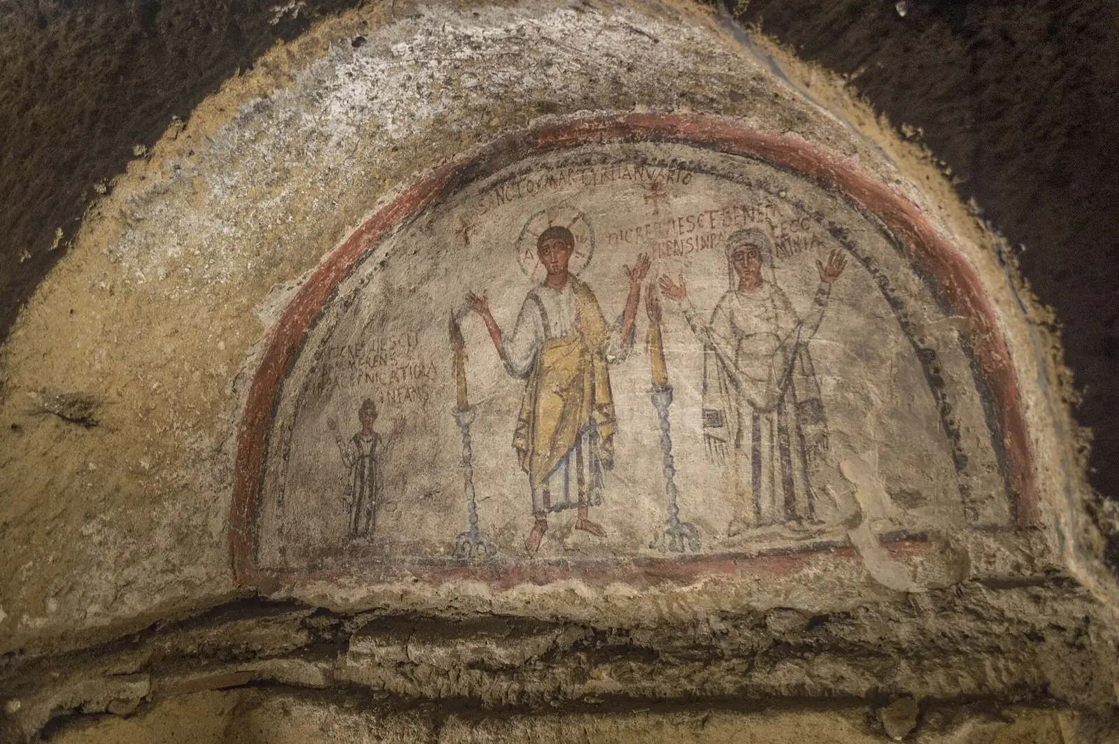 An ancient fresco of saints painted in an arched niche in the catacombs of San Gennaro