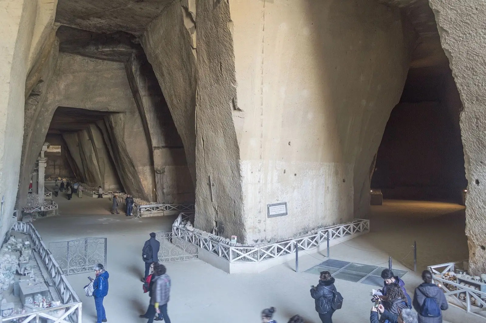 The vast cave halls of the Fontanelle Cemetery carved into yellow tufa, with visitors walking through